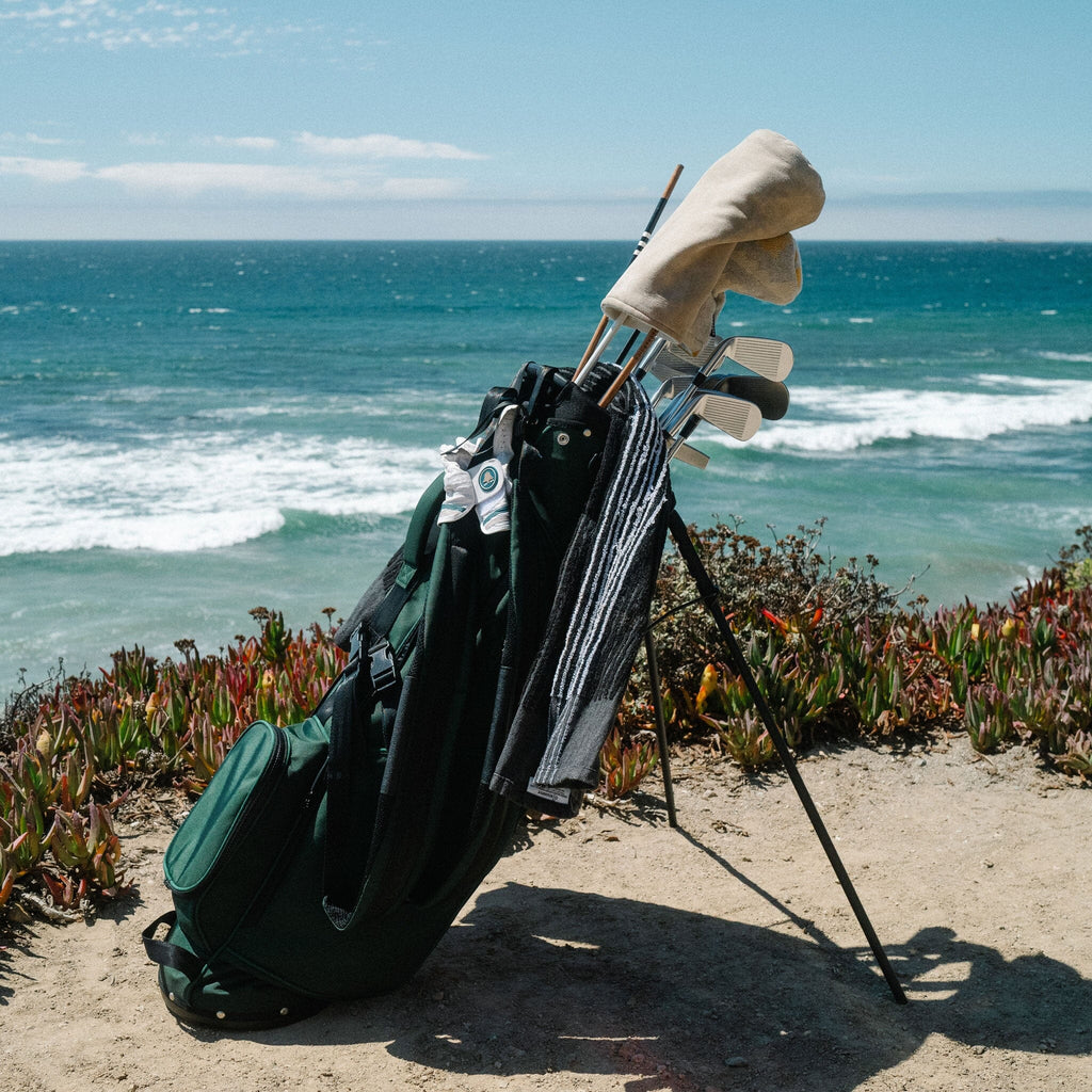 Hudson Sutler Looper Golf Bag in green shown on golf course with stand extended and clubs organized neatly