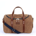 Medium tan canvas commuter bag with leather straps and a navy cross body strap.